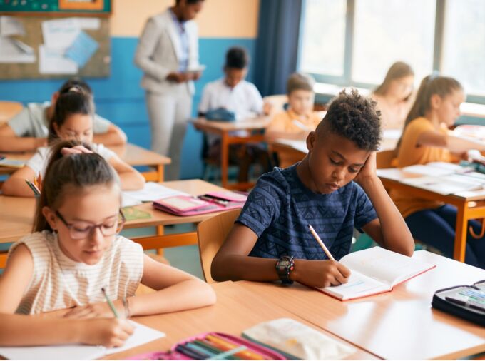 Elementary students writing dictation during class in the classroom.